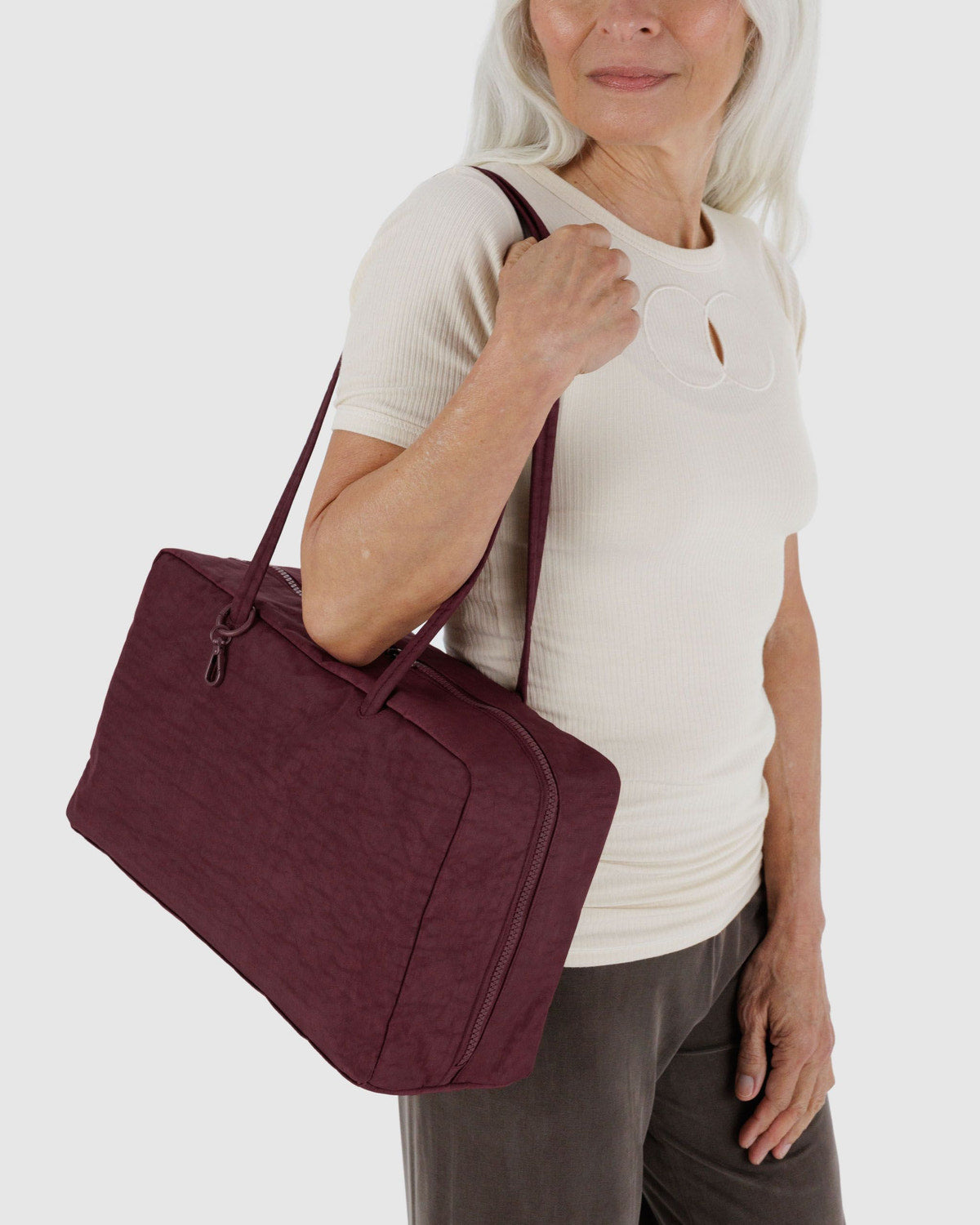 Medium nylon bowler bag on shoulder; burgundy with zipper, side seams, and carry handles.