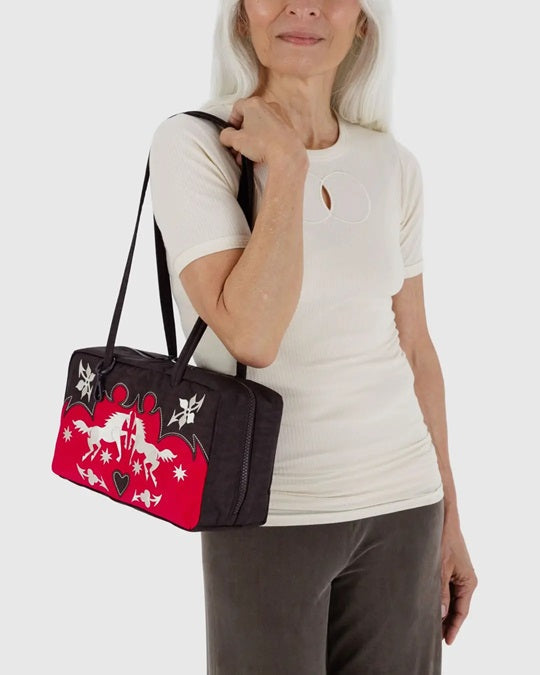 Nylon bowler bag carried on shoulder; black bag with red panel and white applique designs.