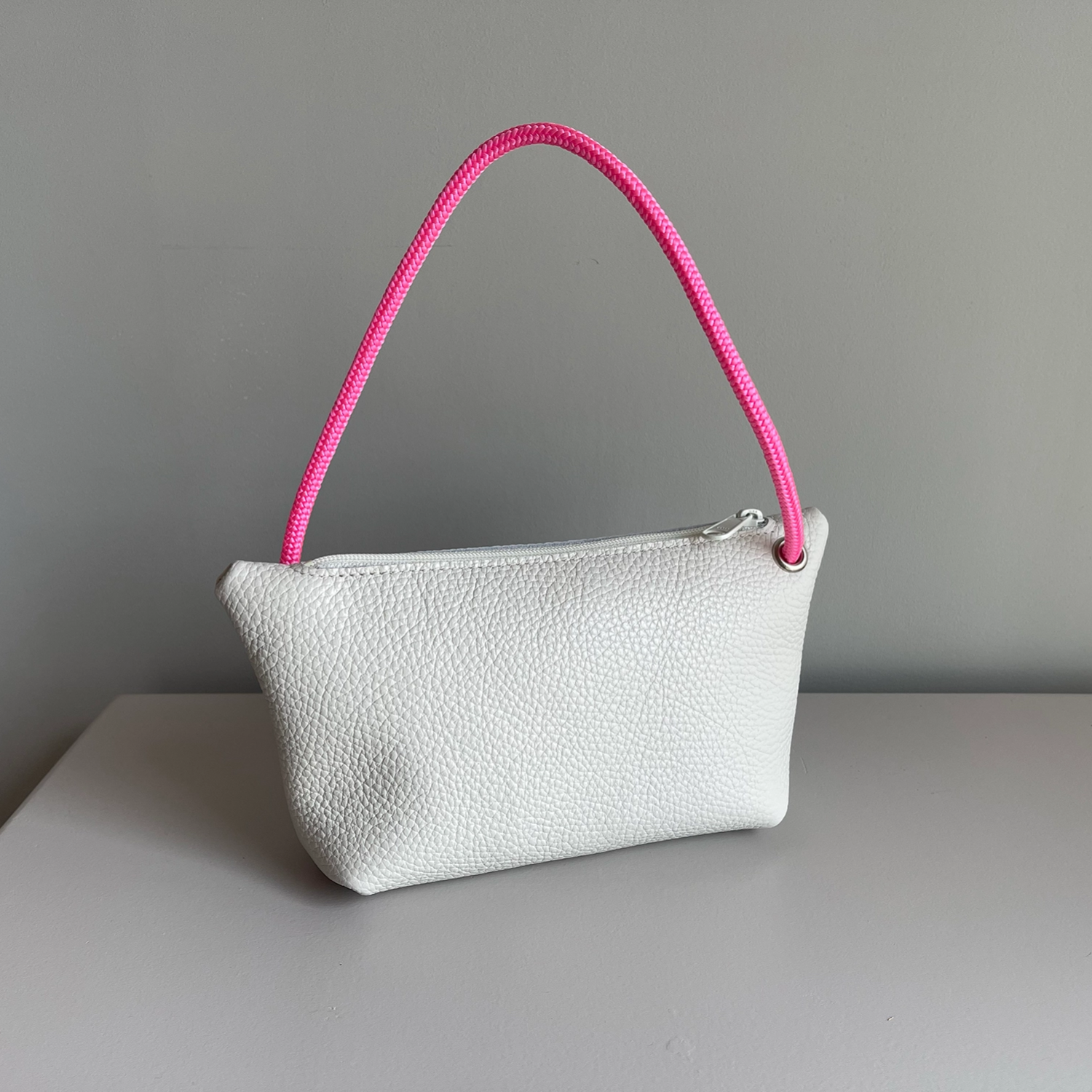 Cream cord pouch with pink braided handle and zipper top.