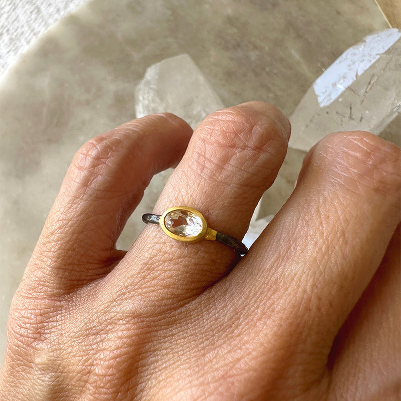 Oval morganite ring on finger; oxidized sterling silver band with gold-toned bezel