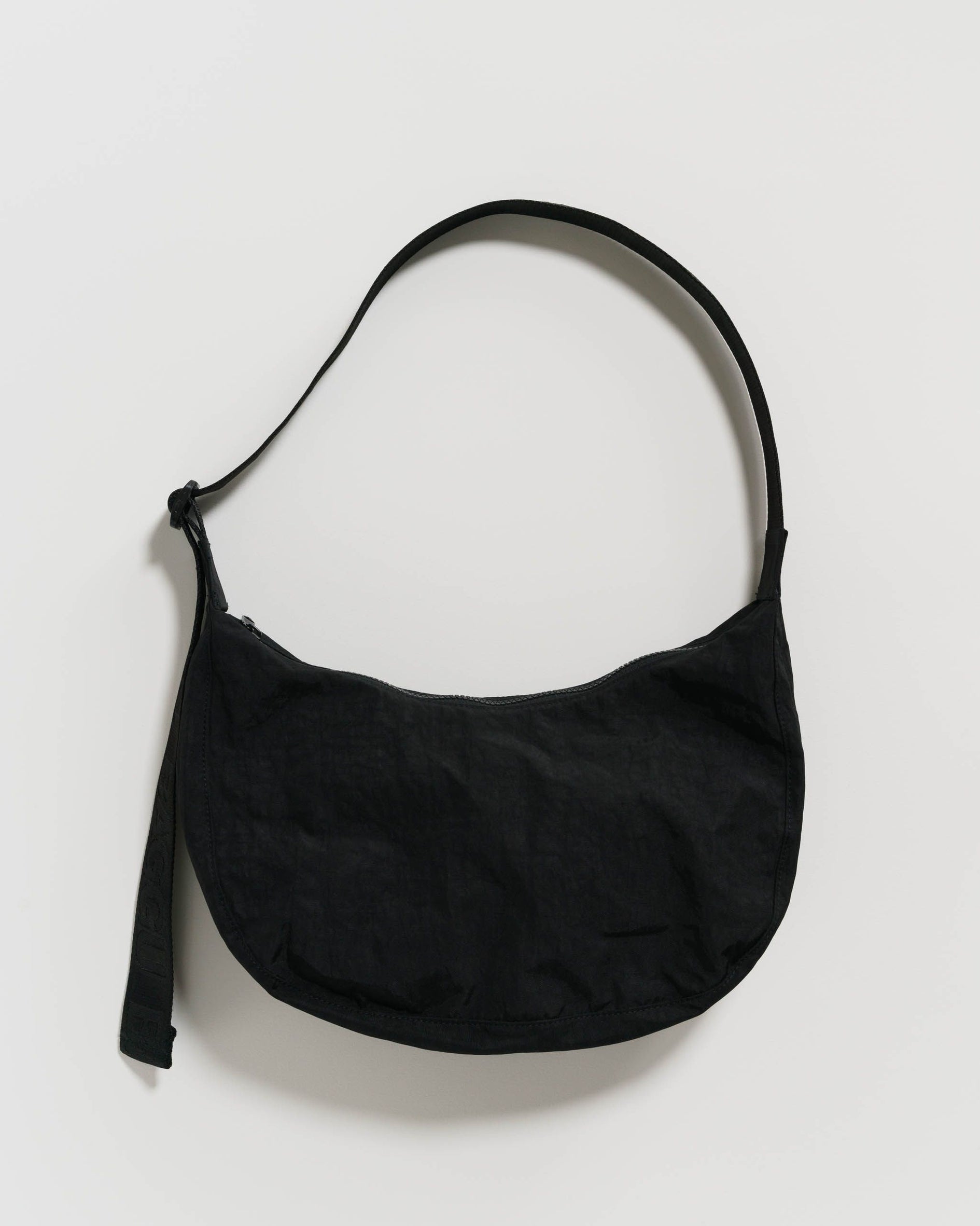 Black nylon crescent bag with long strap and small hanging tag