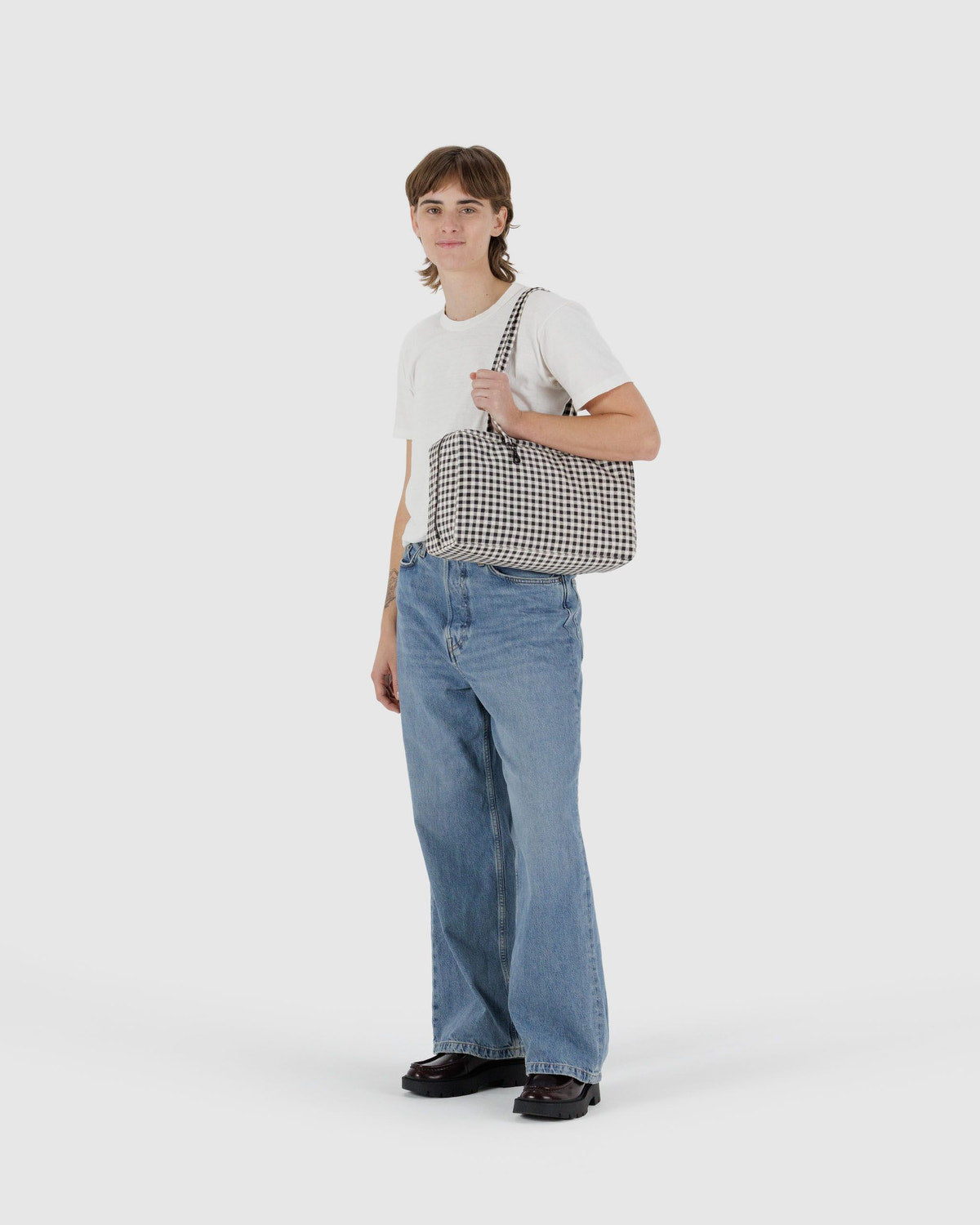 Medium nylon bowler bag held across body; black-and-white gingham with zipper and handles.