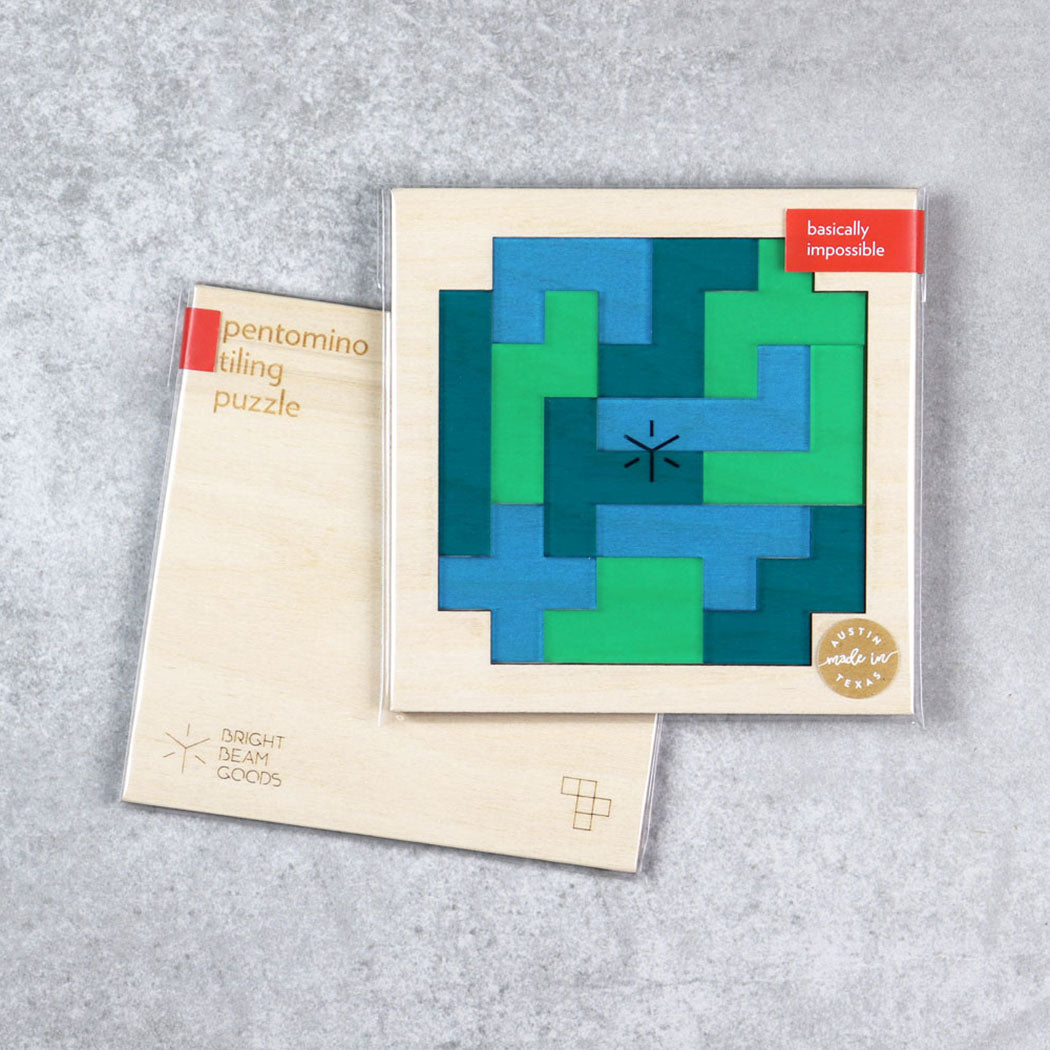 Square pentomino puzzle with teal and green interlocking pieces in a box