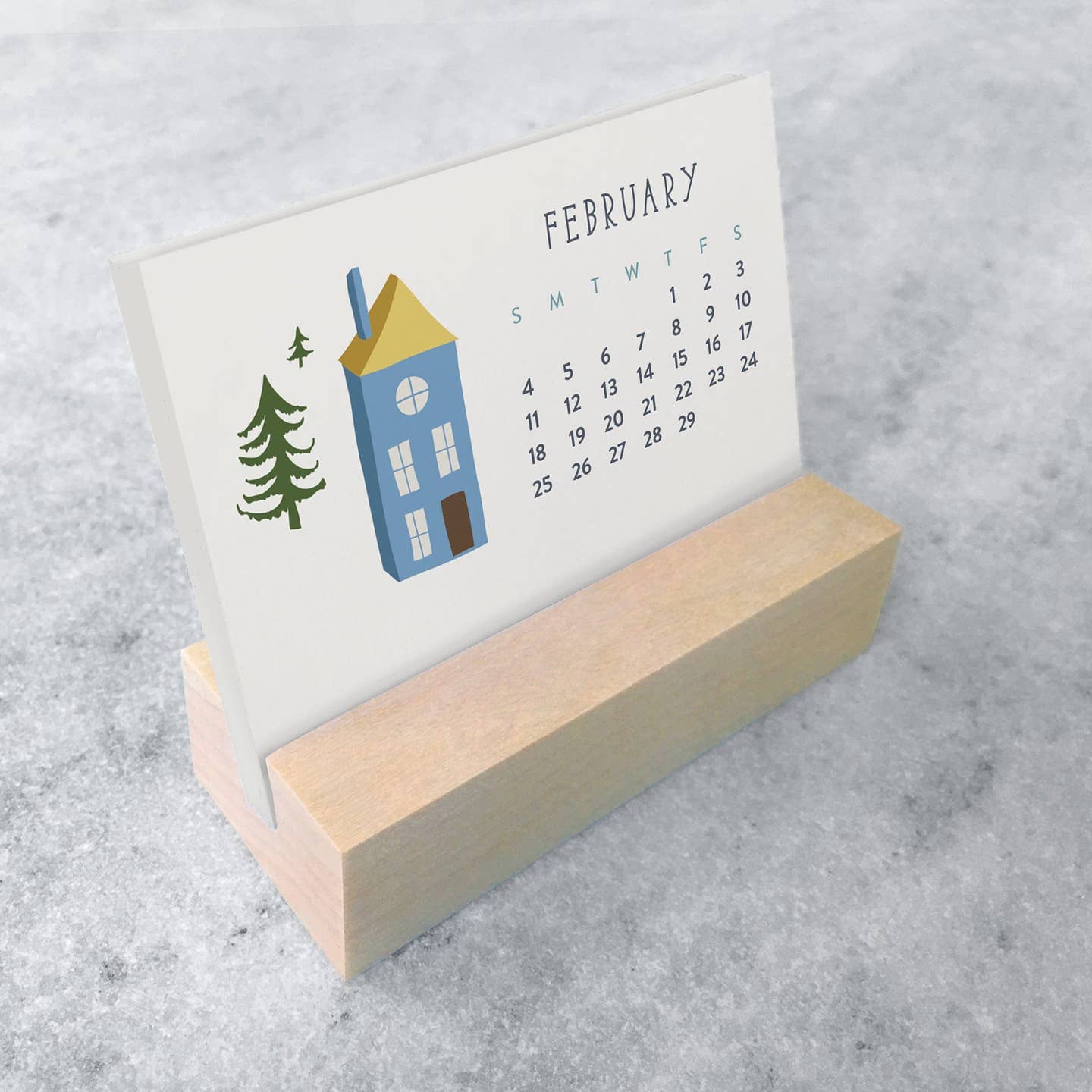 Mini desk calendar showing February, blue building and trees, wooden stand