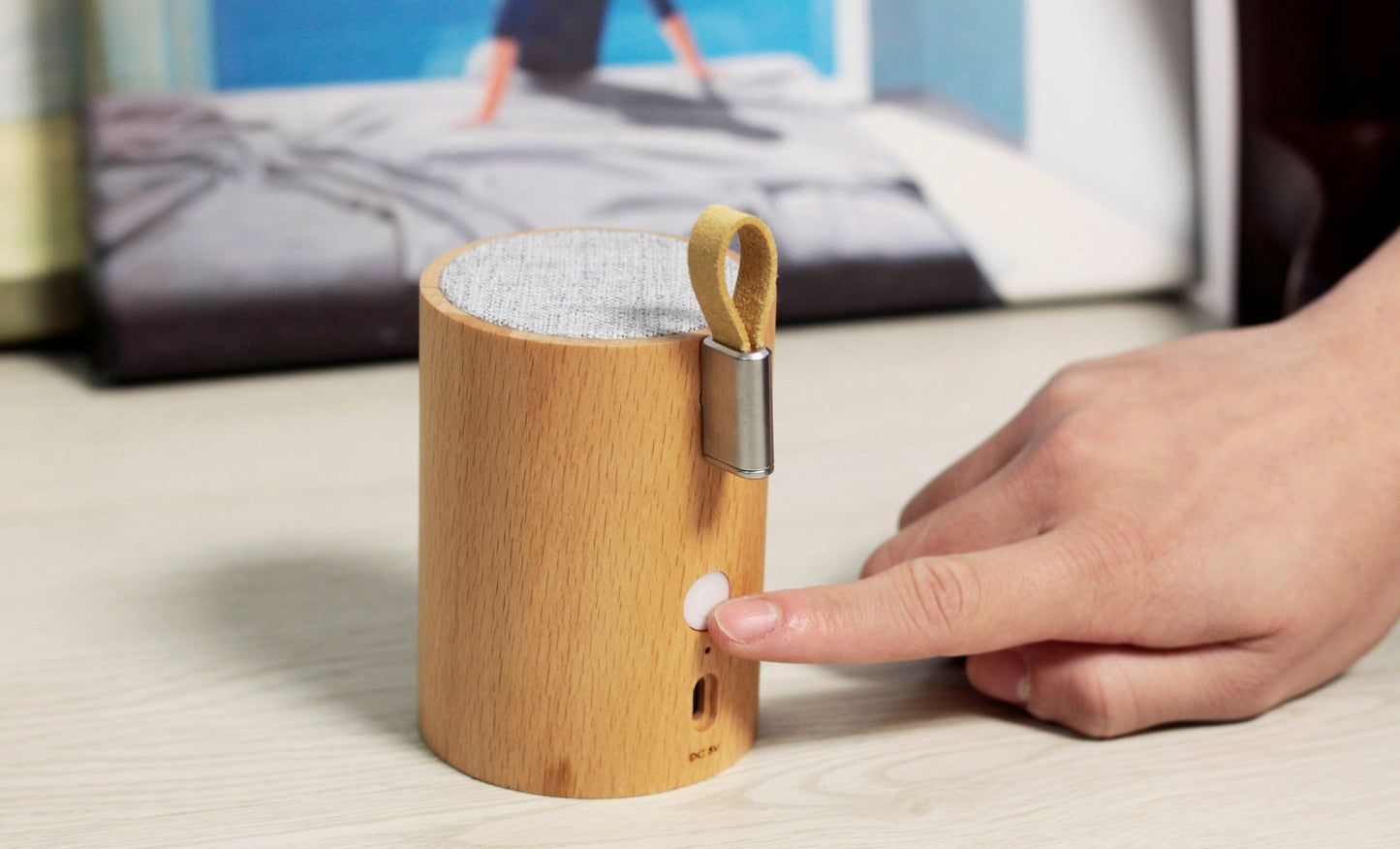 Beech wood drum speaker with front button panel and fabric top under hand