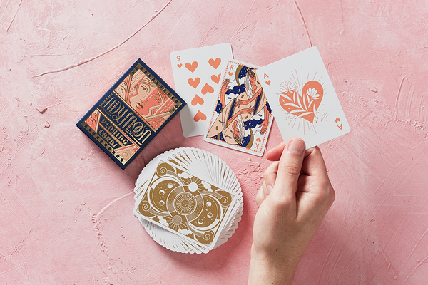 Moon-themed playing cards in hand with illustrated face cards and deck nearby