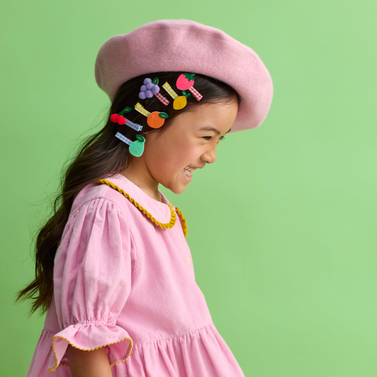 Child wearing fruit-shaped felt hair clips: strawberry, lemon, grapes