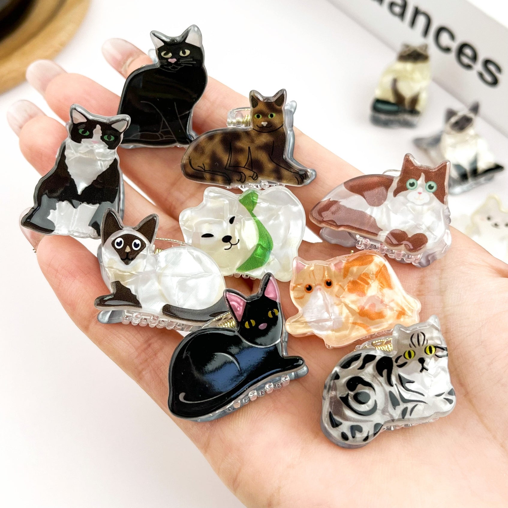 Mini cat hair claws assortment with cat faces in hand, rhinestone edges