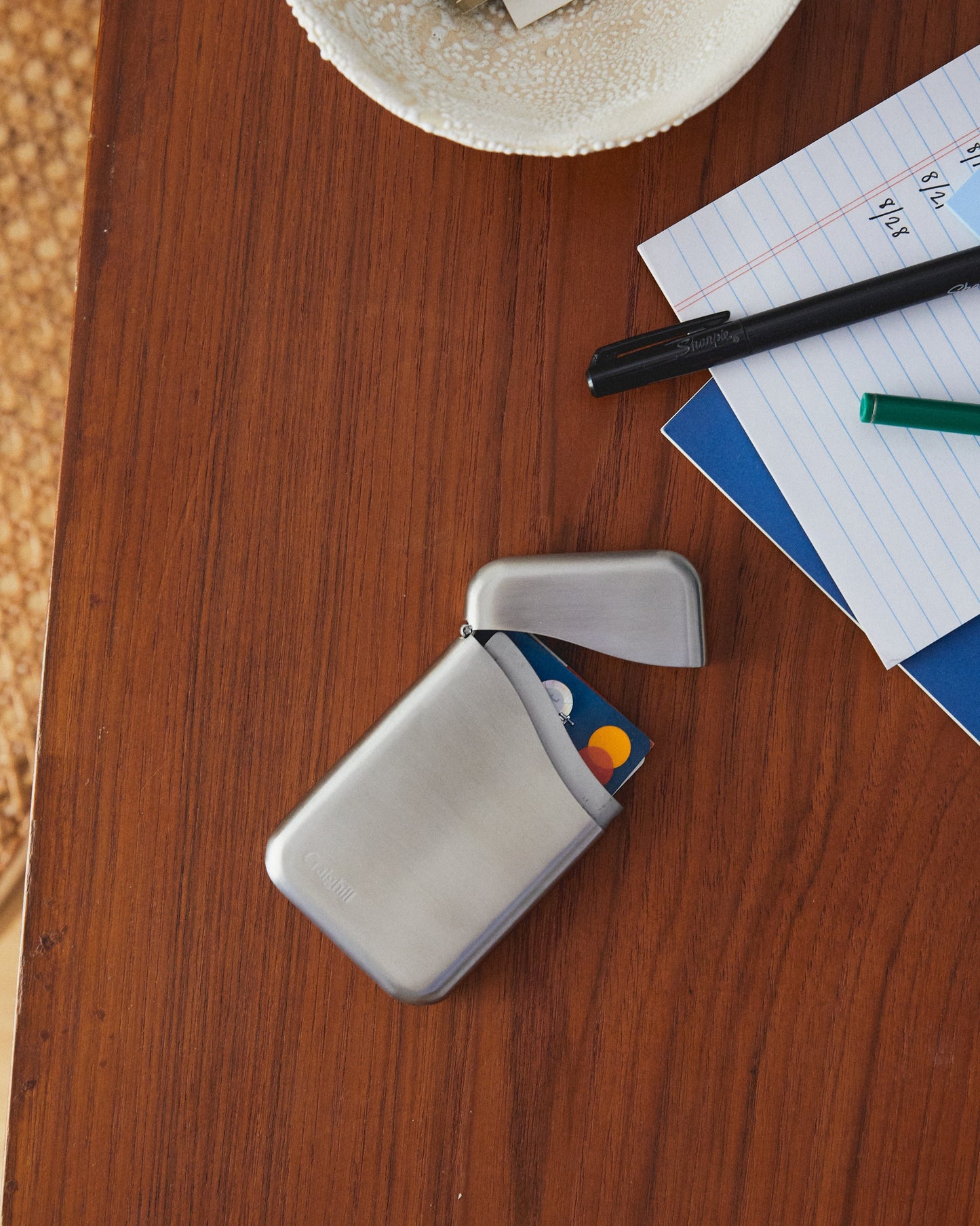 Stainless steel card case open with credit card slot holding cards, curved shape.