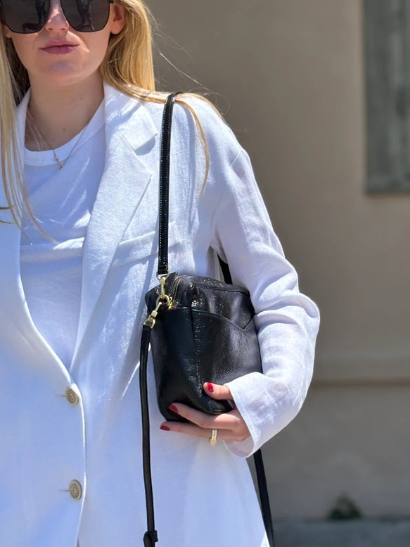 Black crossbody bag with flap front and long adjustable strap, side view