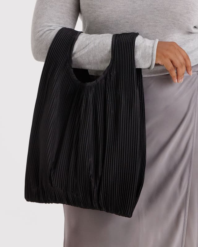 Pleated Baggu tote in black pleated stripes, carried by the U-shaped opening