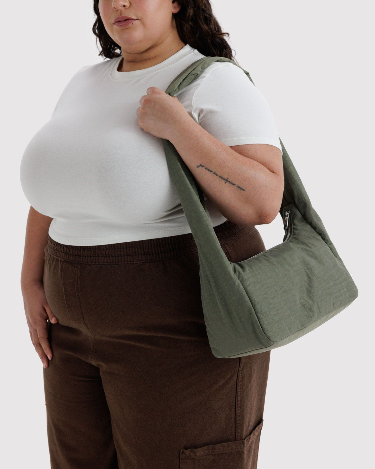 Olive green nylon shoulder bag worn on shoulder, rounded triangular shape.