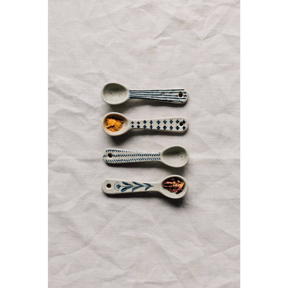 Mini spoon assortment with four small spoons, blue motifs, speckled bowls, and end holes