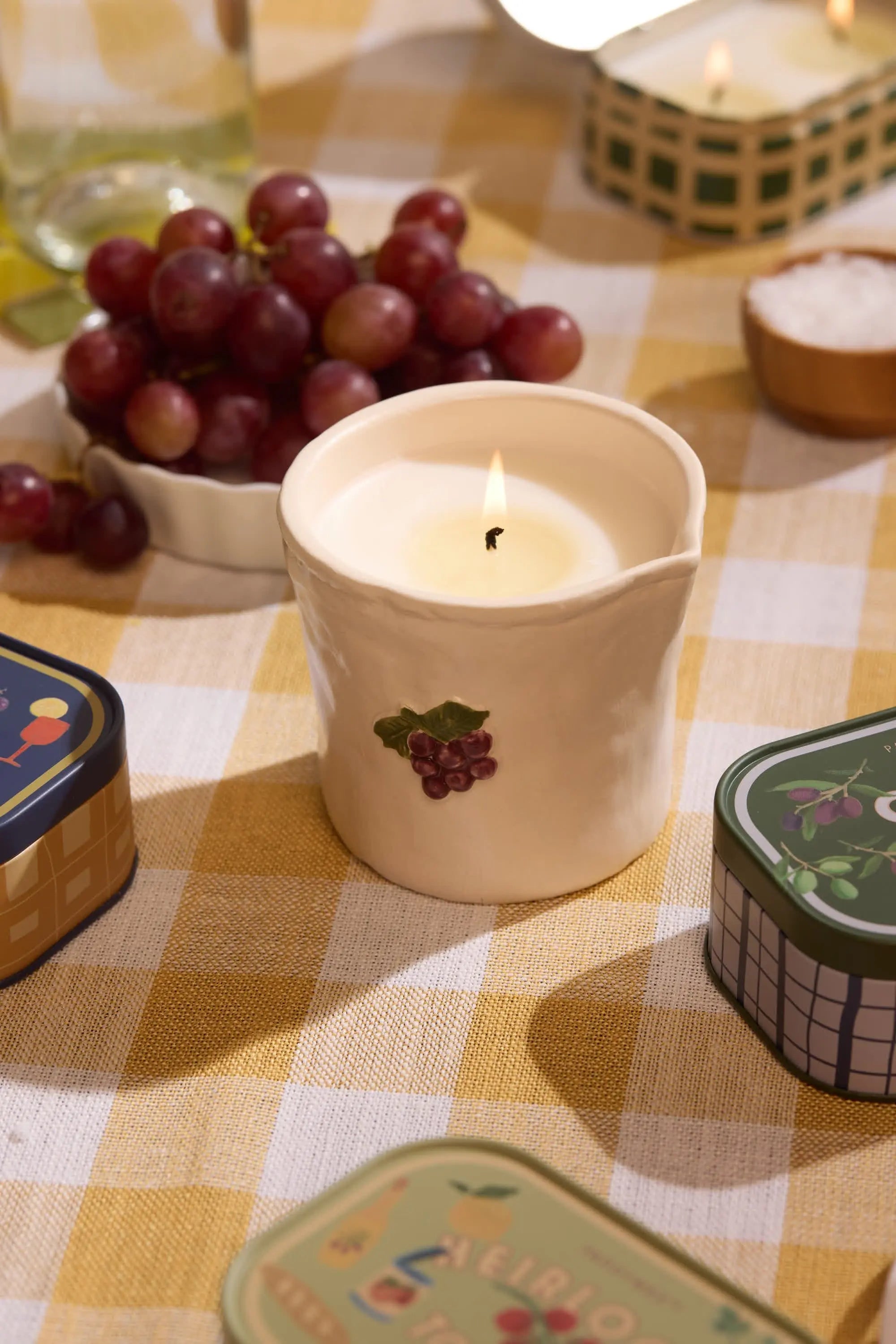 Cream bistro 8 oz bordeaux grape candle with lit wick and grape leaf label