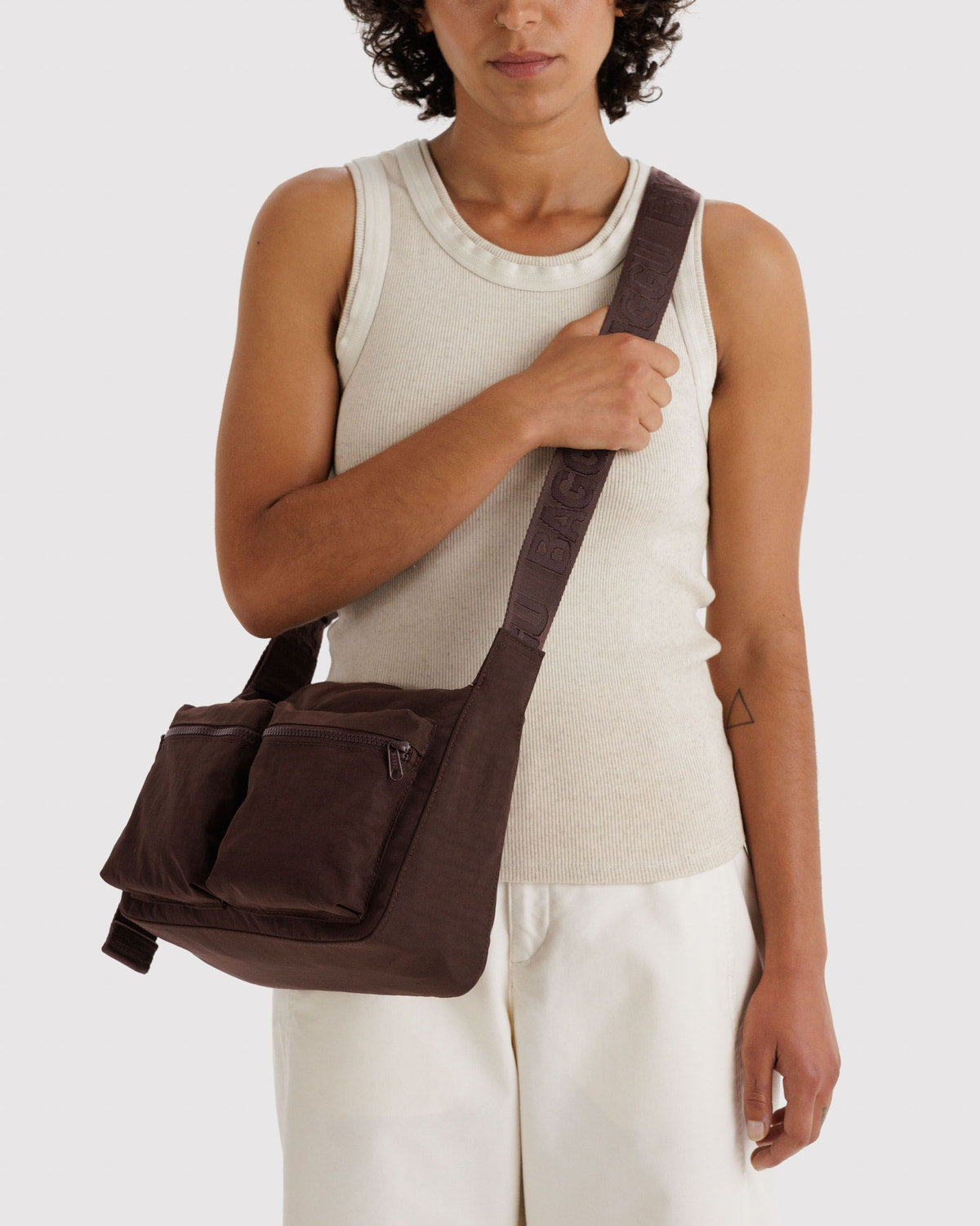 Brown cargo crossbody bag worn across body with front zip pockets and adjustable strap.