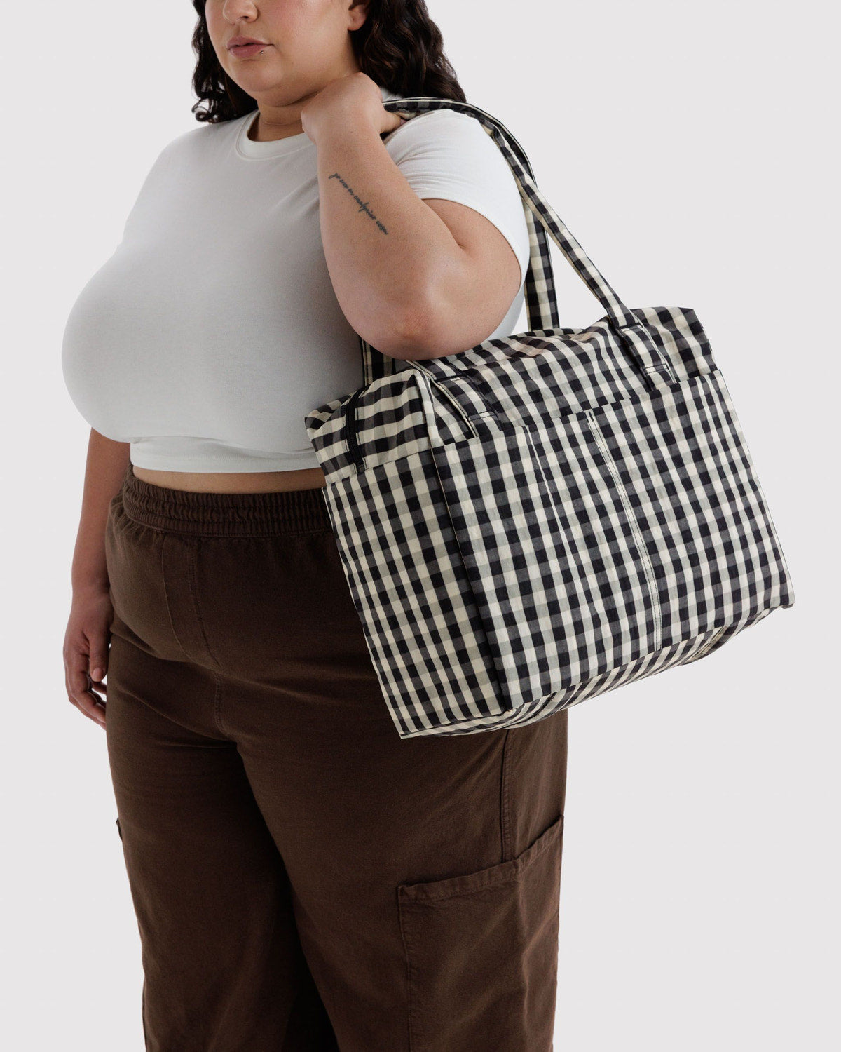 Small Cloud carry-on tote in black-and-cream gingham being carried by a person