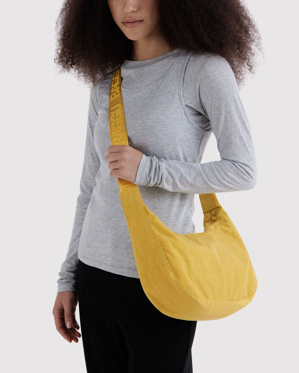 Medium nylon crescent bag in mustard yellow worn crossbody on model