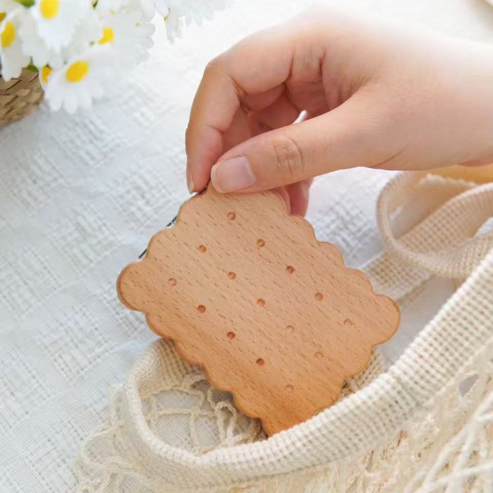 Beech wood biscuit-shaped pocket mirror with dotted pattern, held in hand.