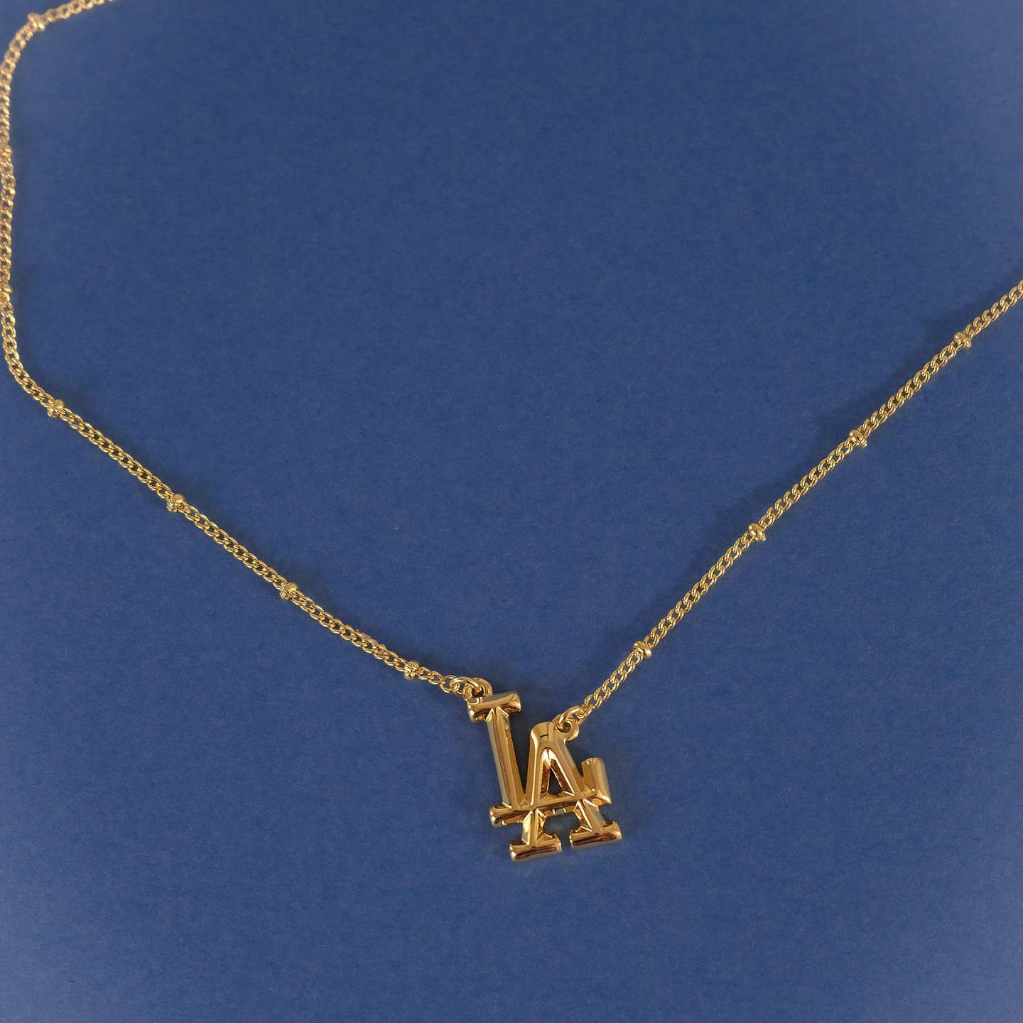 Gold chain necklace with LA Dodgers logo charm pendant, angled close view