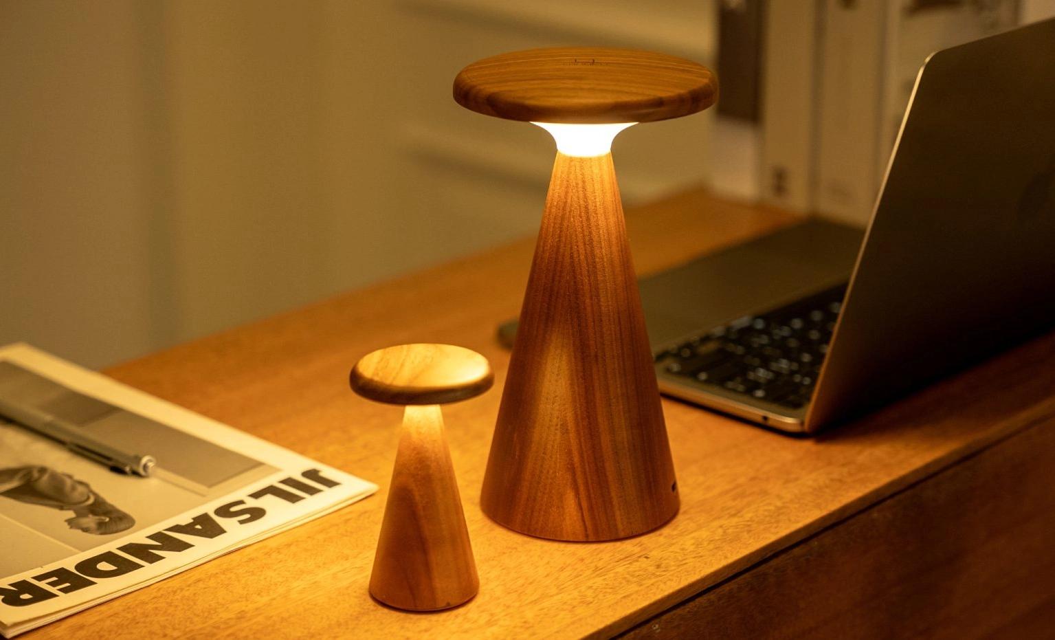 Sylva mini ash table lamp, lit, with wooden pedestal and cream conical shade