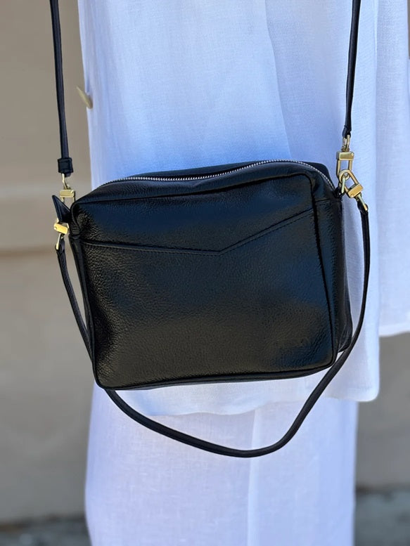 Black crossbody bag with zip top, front panel, and gold-tone hardware