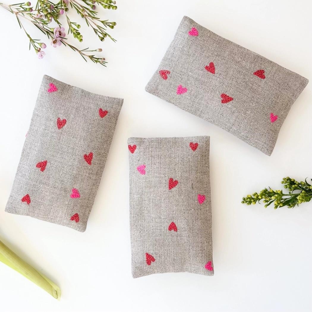 Gray sachet pouches with scattered micro heart motifs in red and pink, three-pack.