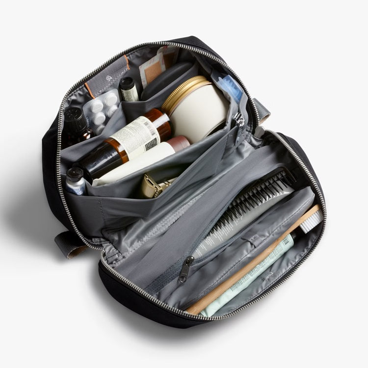 Black toiletry kit open with inner pockets and elastic item holders