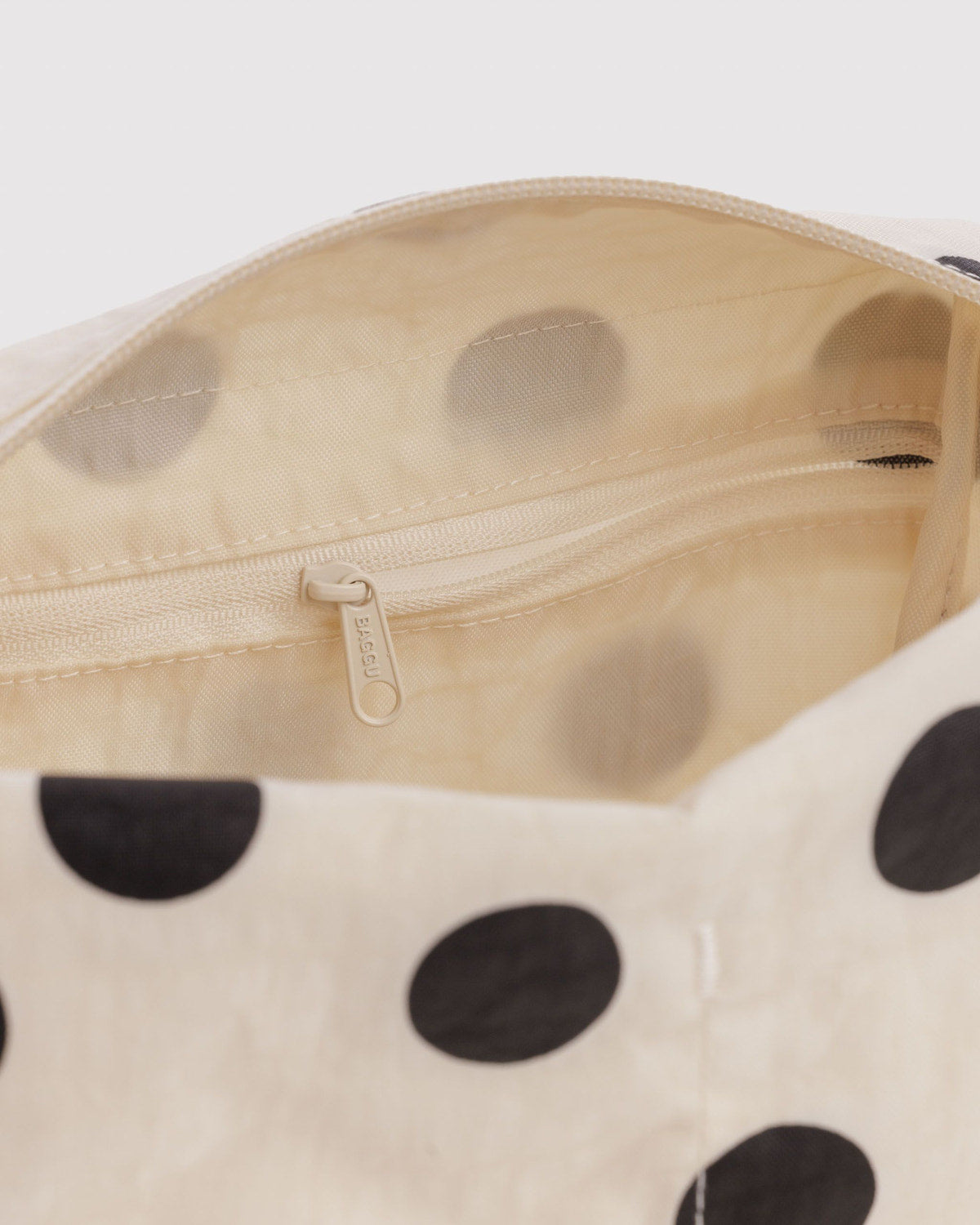 Cream dopp kit interior with black polka-dot exterior and visible zipper closure