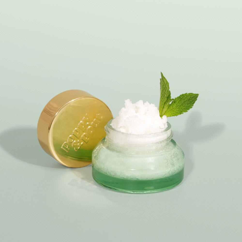 Mint lip scrub jar with white scrub topping and gold lid, plus mint leaf