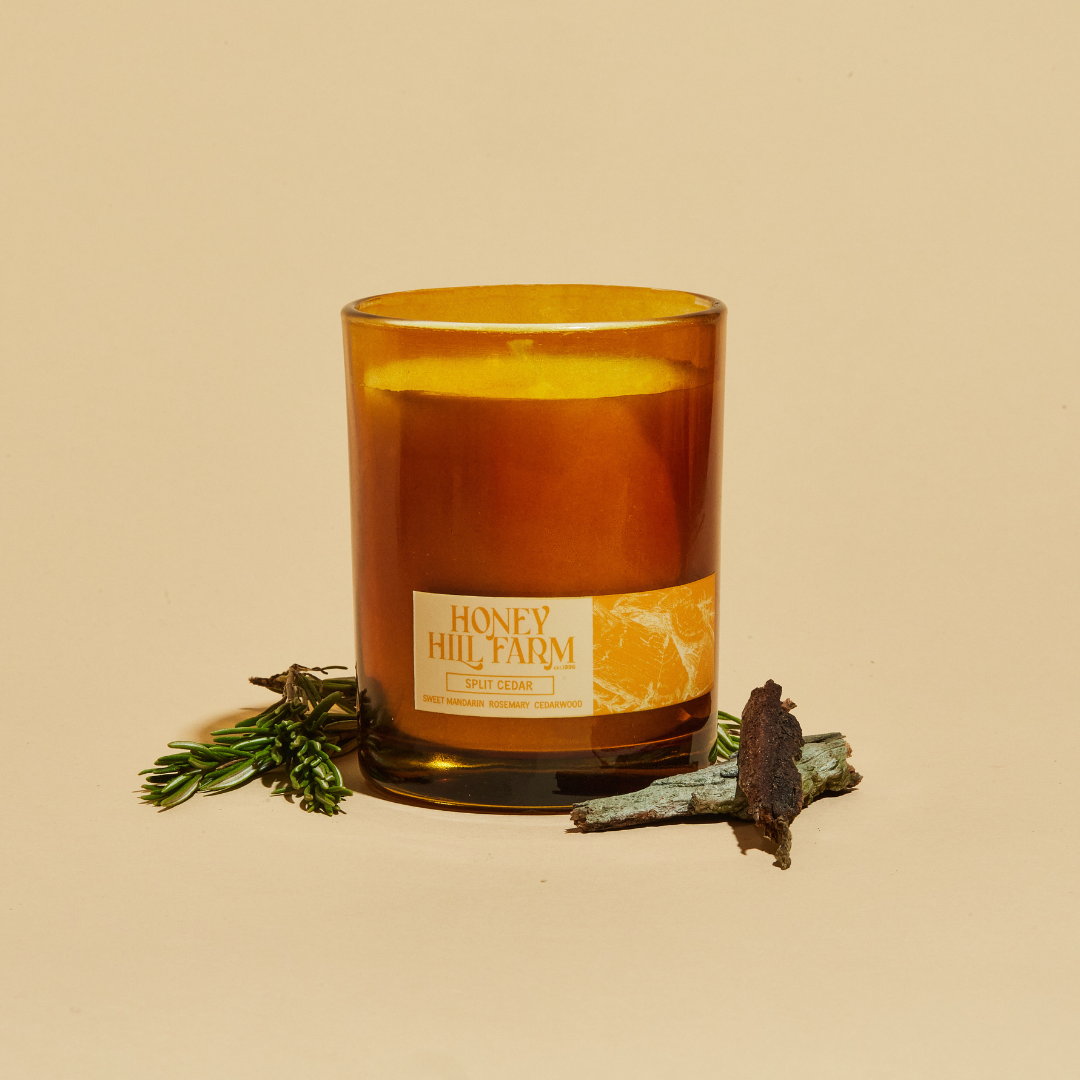 Amber glass candle with 'Honey Hill Farm' label, with herbs and wood pieces