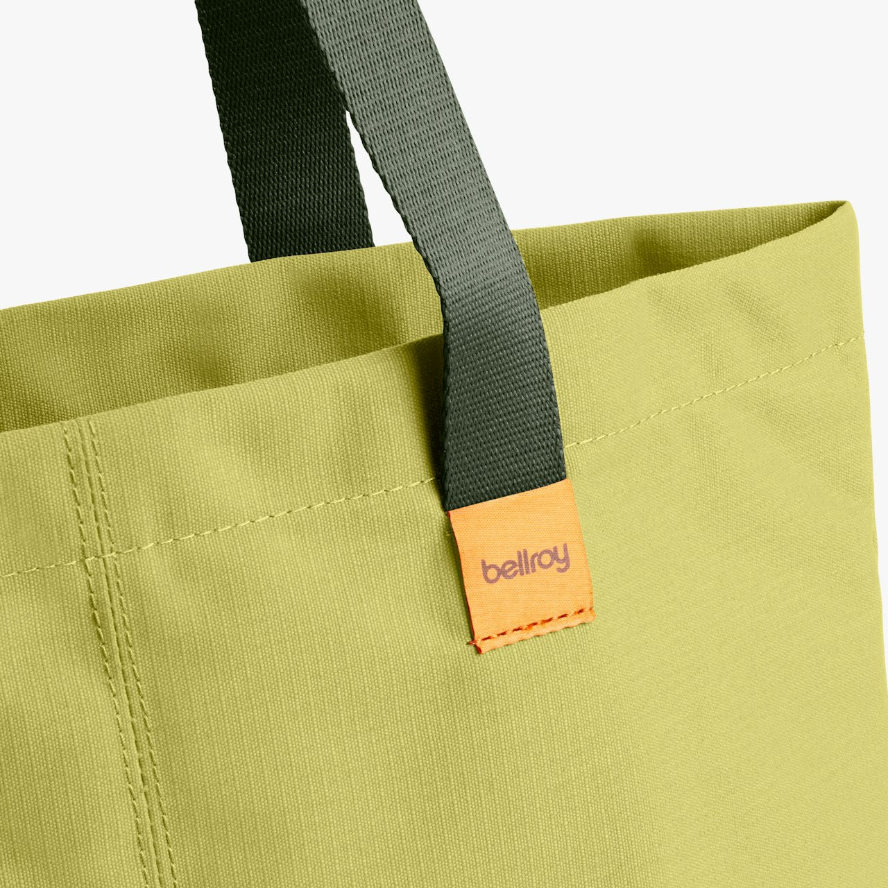 City tote bag strap and orange brand label patch on bright yellow fabric.