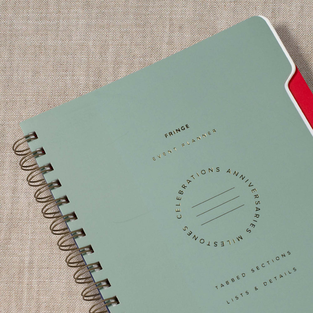 Close-up: sage green spiral event planner cover with printed circular event text