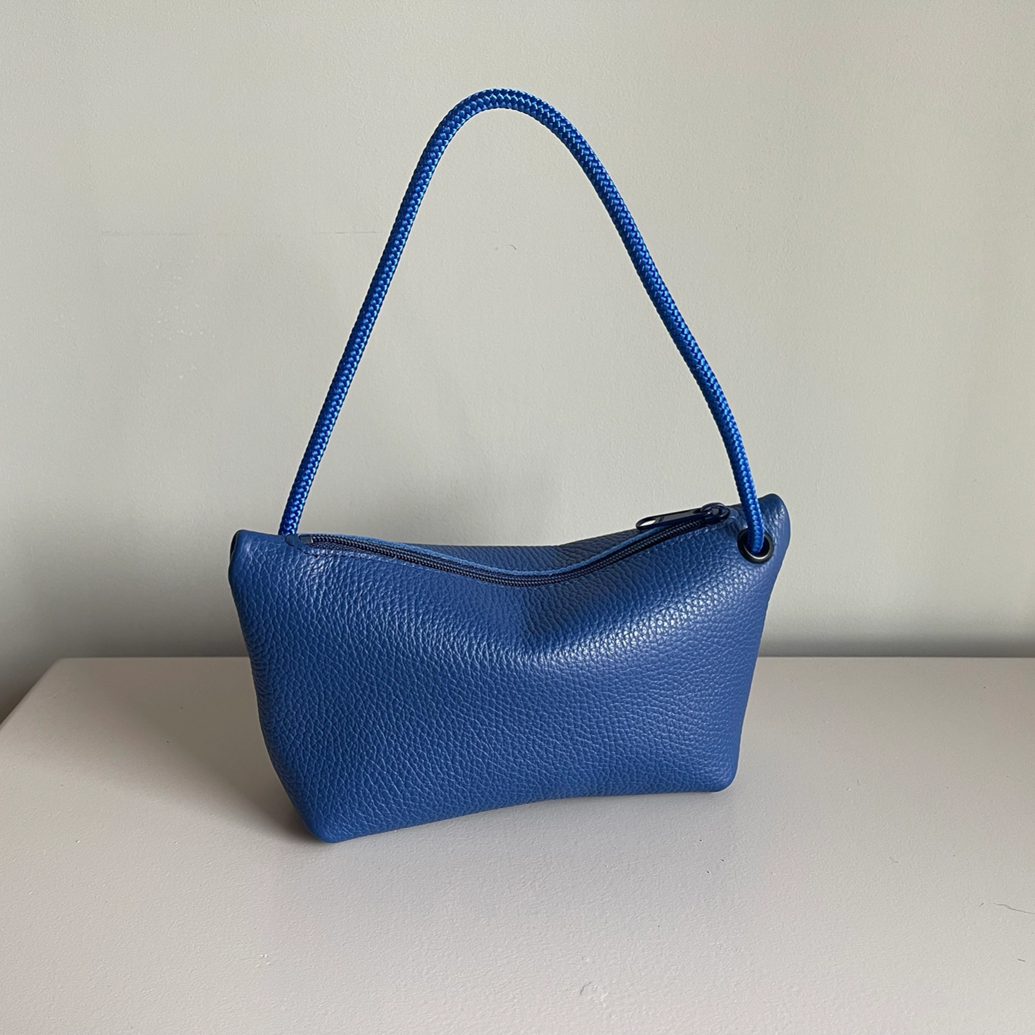 Navy cord pouch with textured leather look and braided top handle.