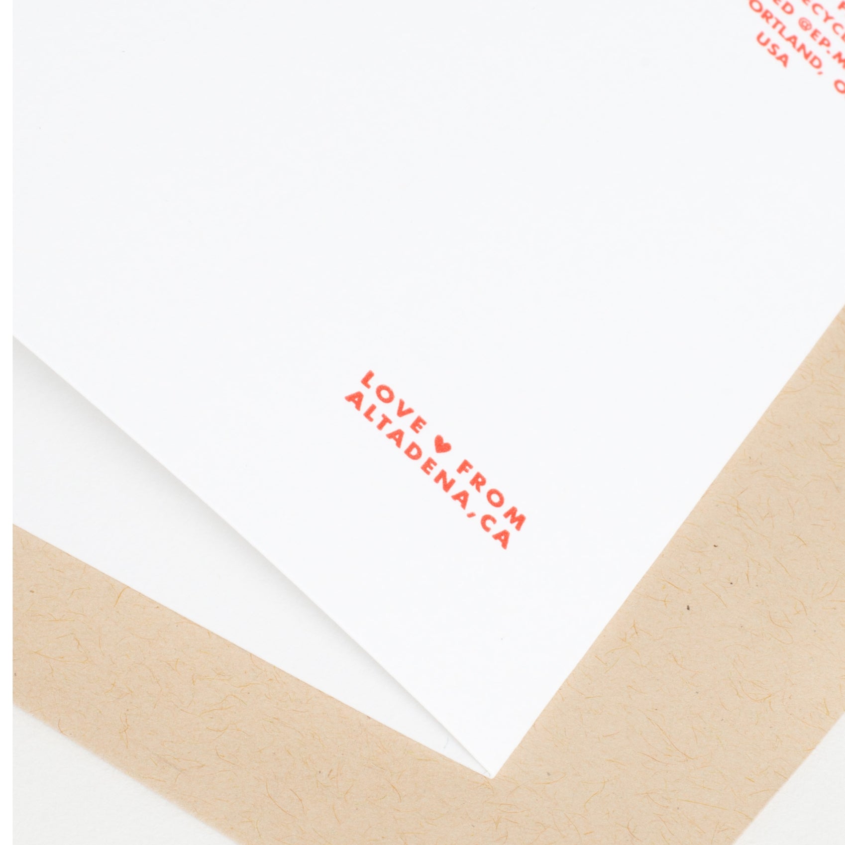 Card corner with red letterpress "LOVE FROM..." text and a kraft envelope
