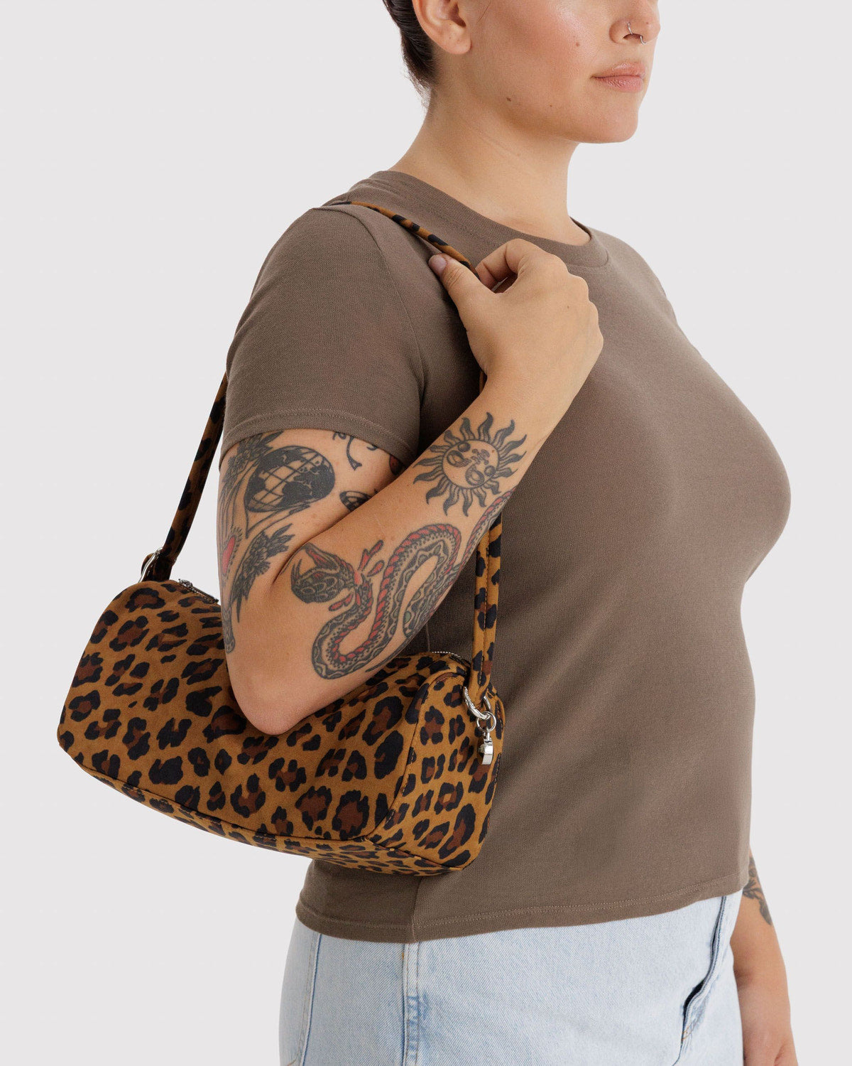 Leopard print nylon loaf bag worn over shoulder; curved handle and top zipper.