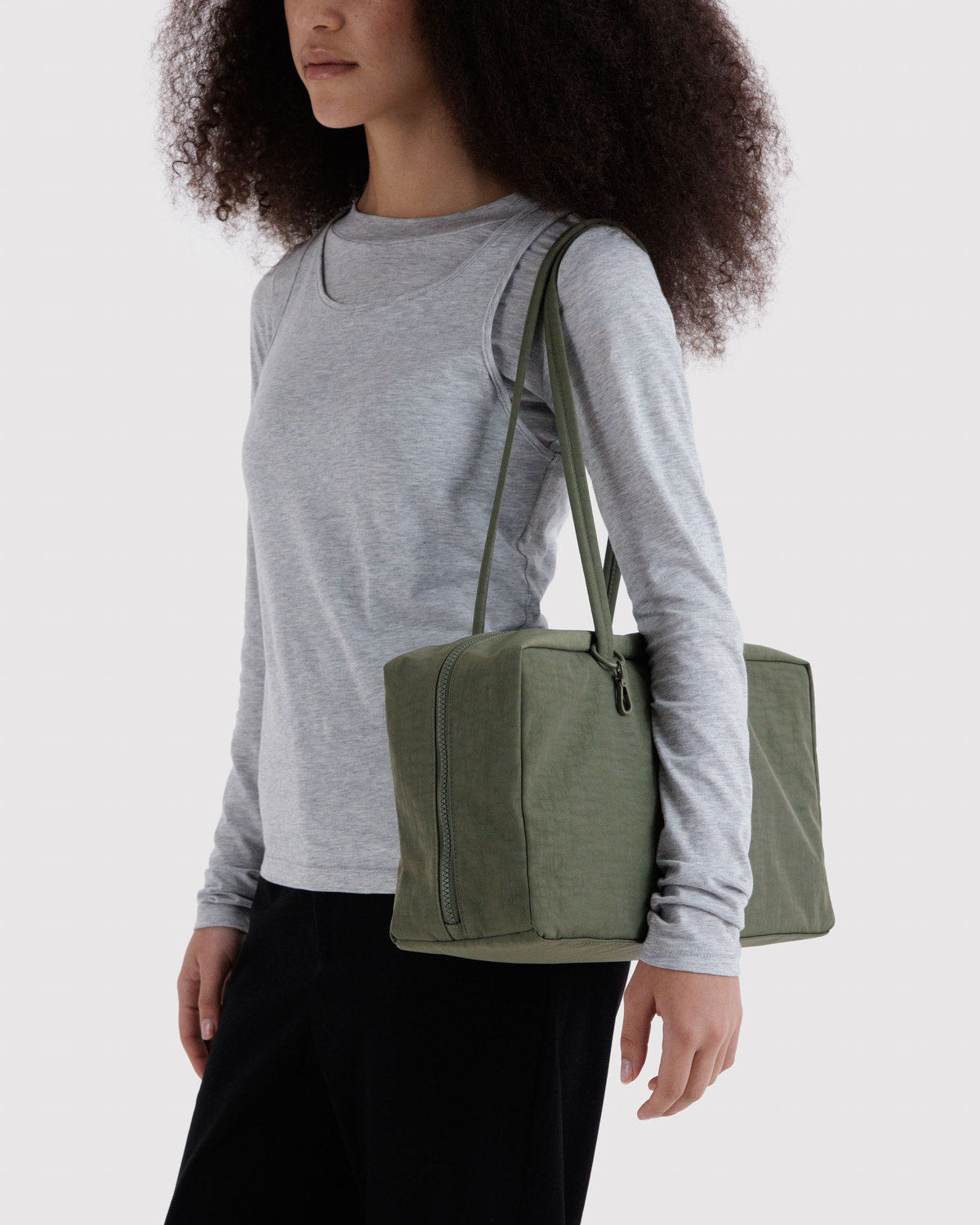 Medium nylon bowler bag carried at side; olive green with zipper closure and handles.