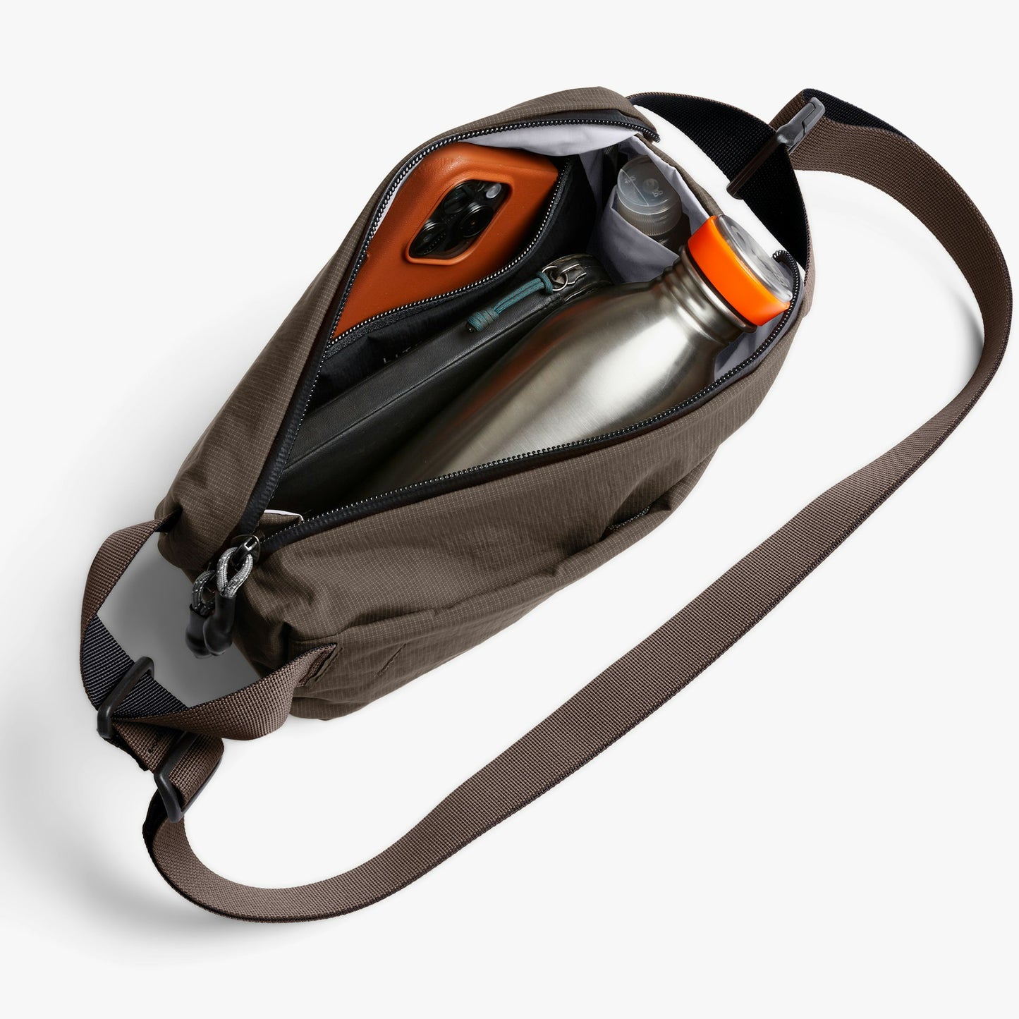 Mini sling bag opened, showing orange phone case and small items inside.