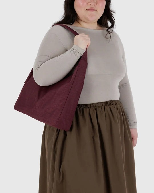 Burgundy nylon shoulder bag worn crossbody with curved top handles