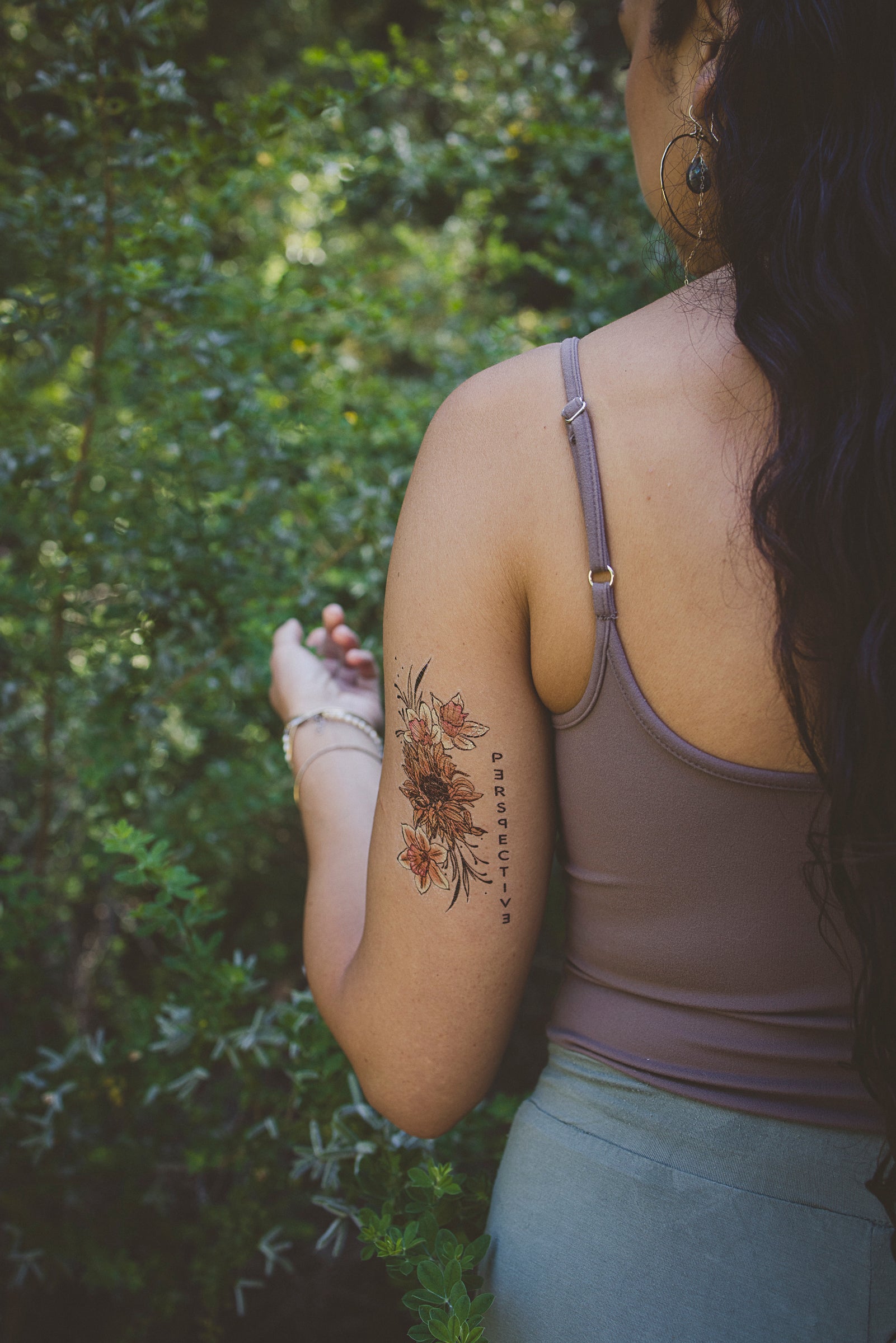 Small floral temporary tattoo on upper arm with sunflower and leaves
