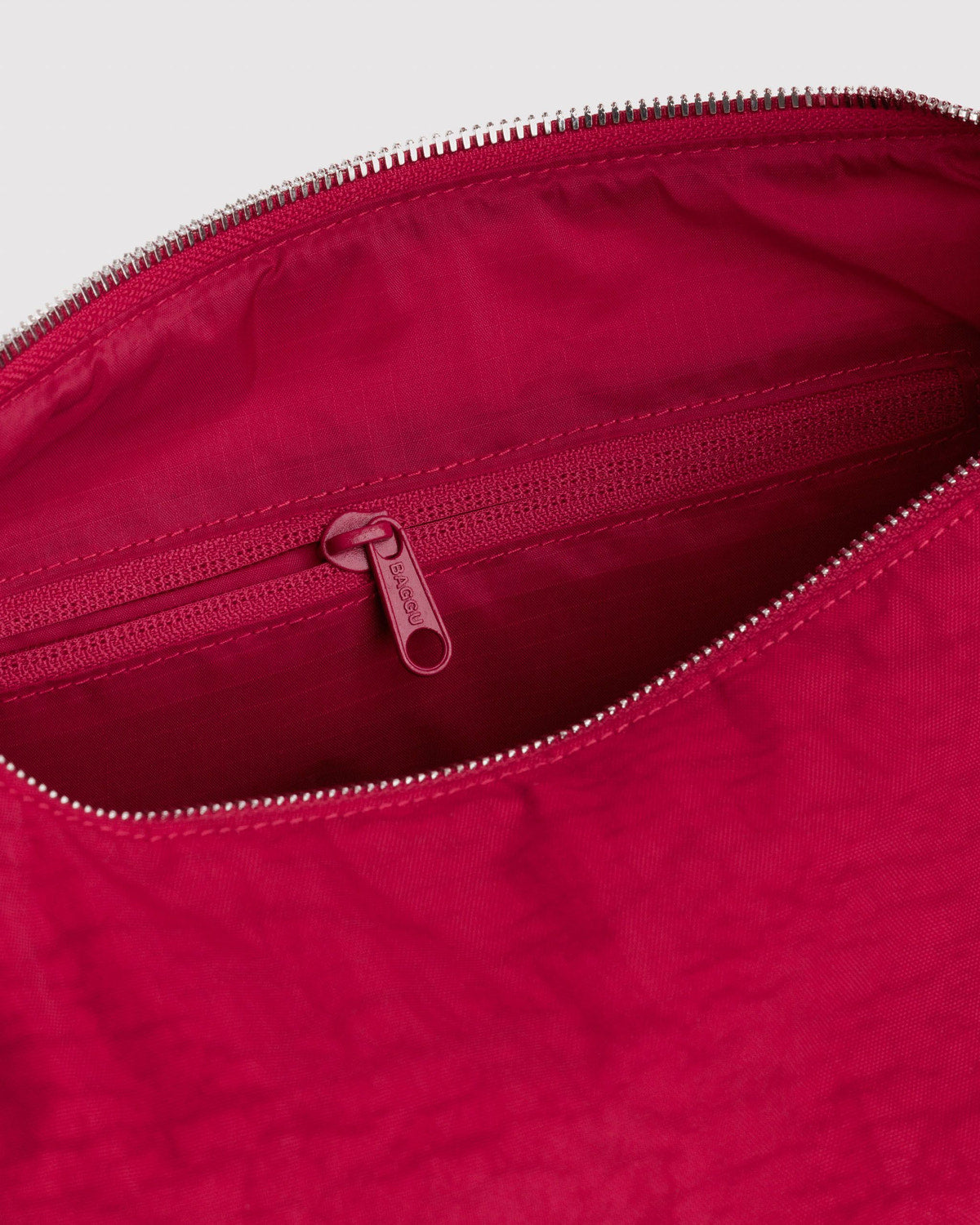 Red nylon bag interior with zippered pocket and silver zipper pull.