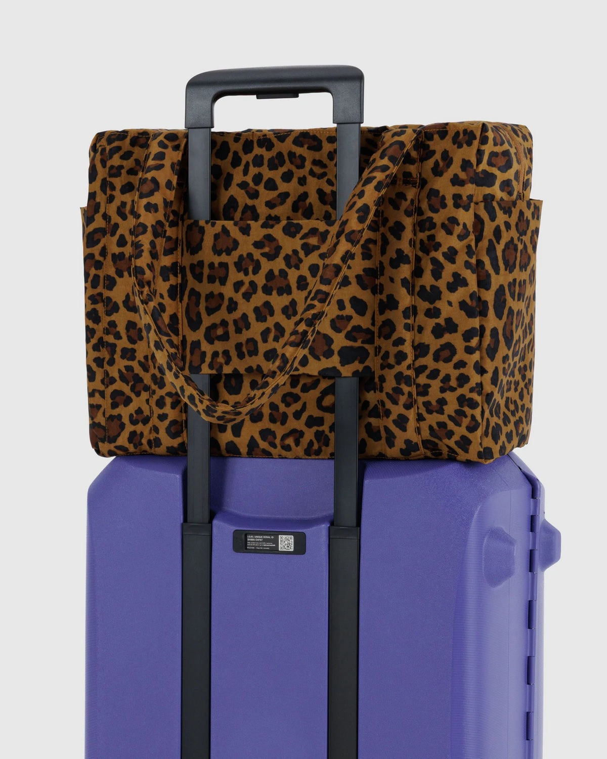 Small Cloud carry-on with leopard tote cover over purple hard-shell base and black handle