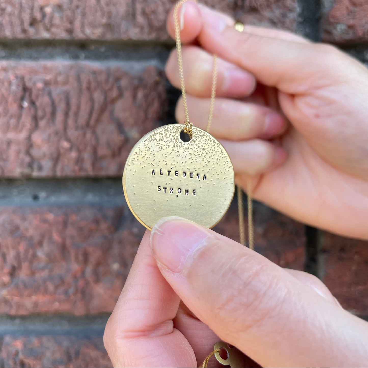 Gold round diamond-dusted pendant on chain with Altadena Strong engraving and black hole