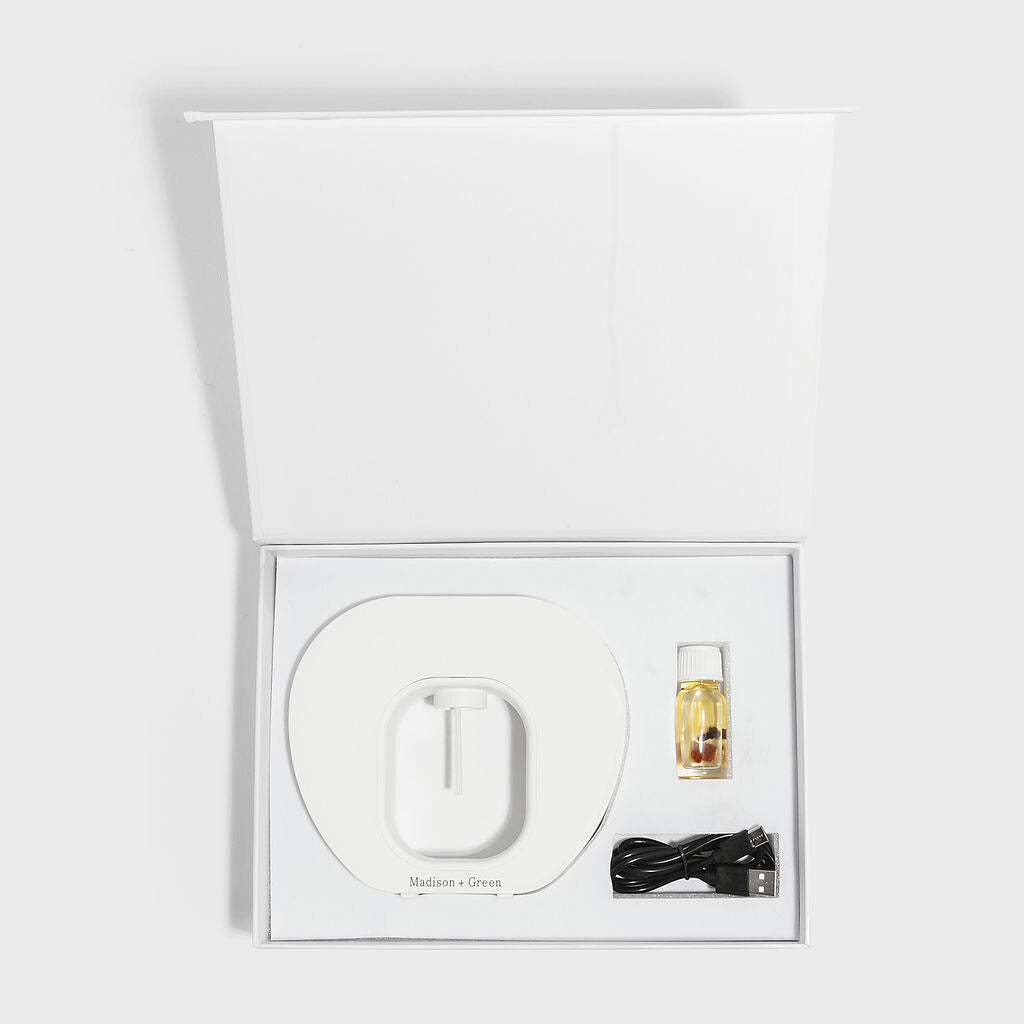 Nebulizing diffuser set in open box with round base, bottle, and black power adapter