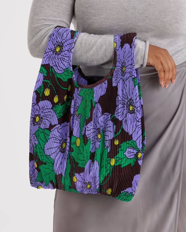 Pleated Baggu tote with purple and green floral print, held by the top handle opening