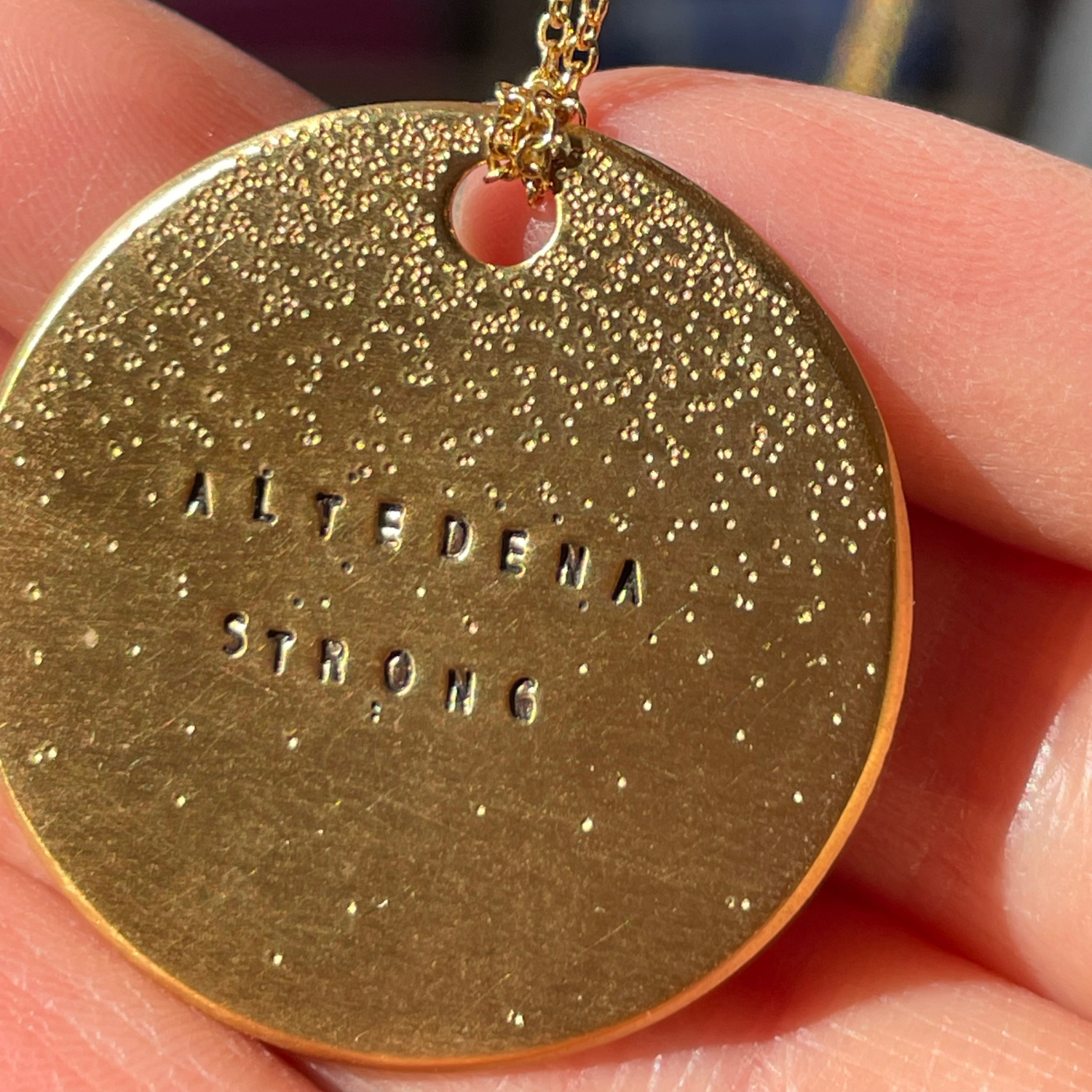 Gold round pendant with diamond-dusted finish and engraved 'ALTEDENA STRONG' text