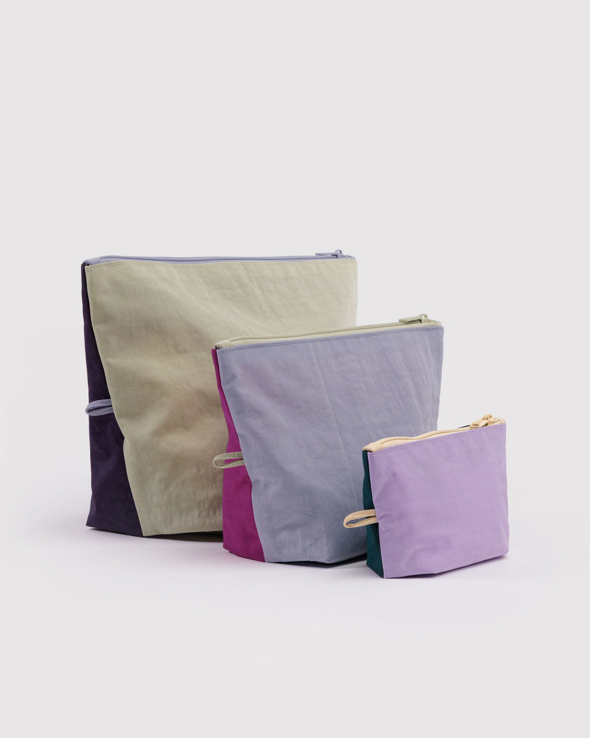Set of three zip pouches in beige, lavender, and purple with drawstring ties