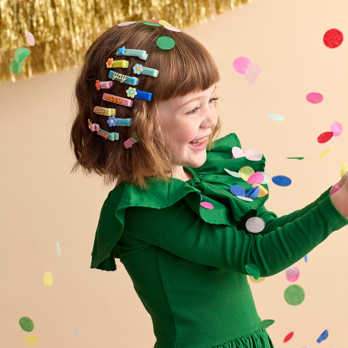 Girl wearing pastel enamel hair clips with star and 'day' lettering on brown hair