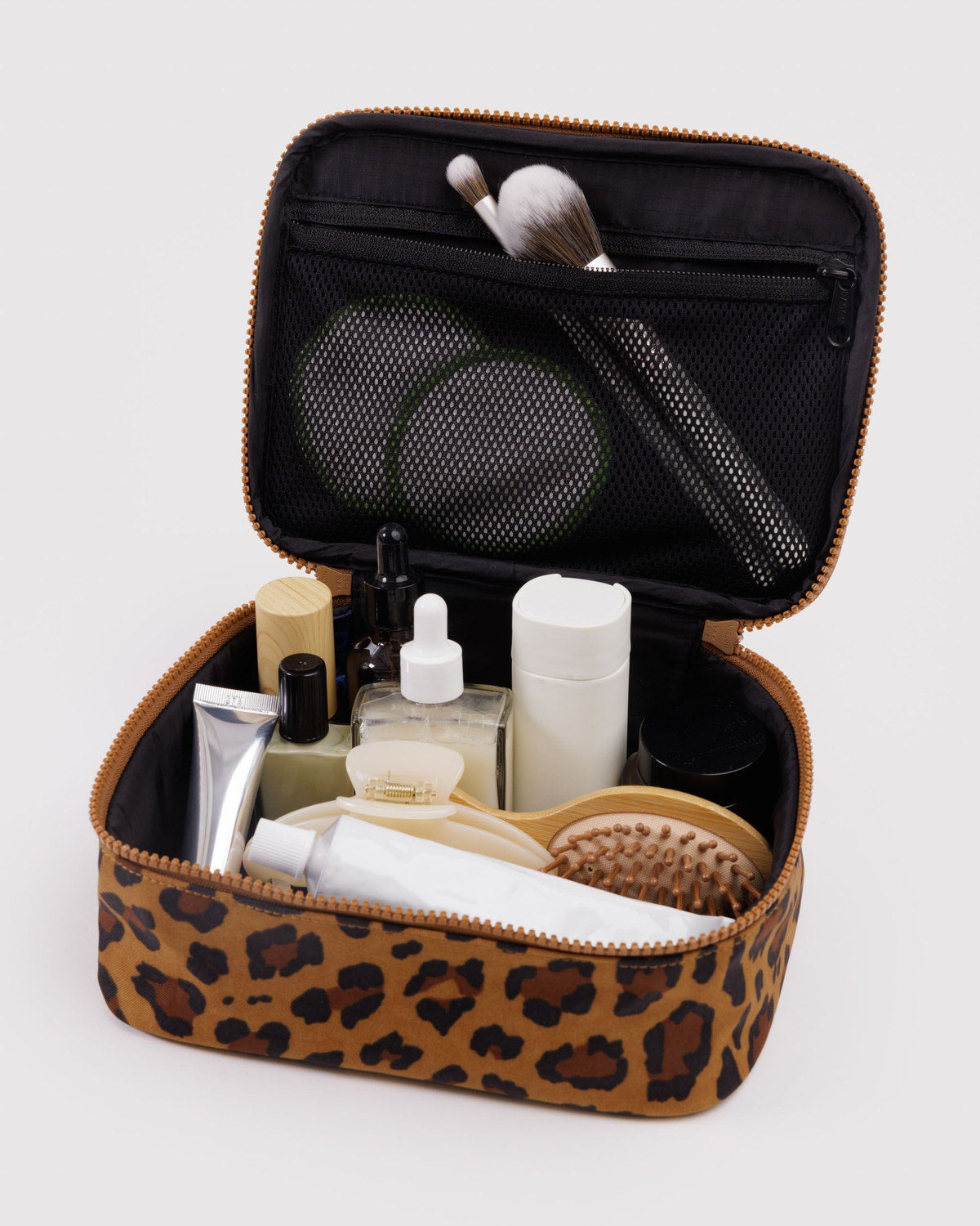 Small cosmetic case, leopard print with open top showing bottles, brush, and comb