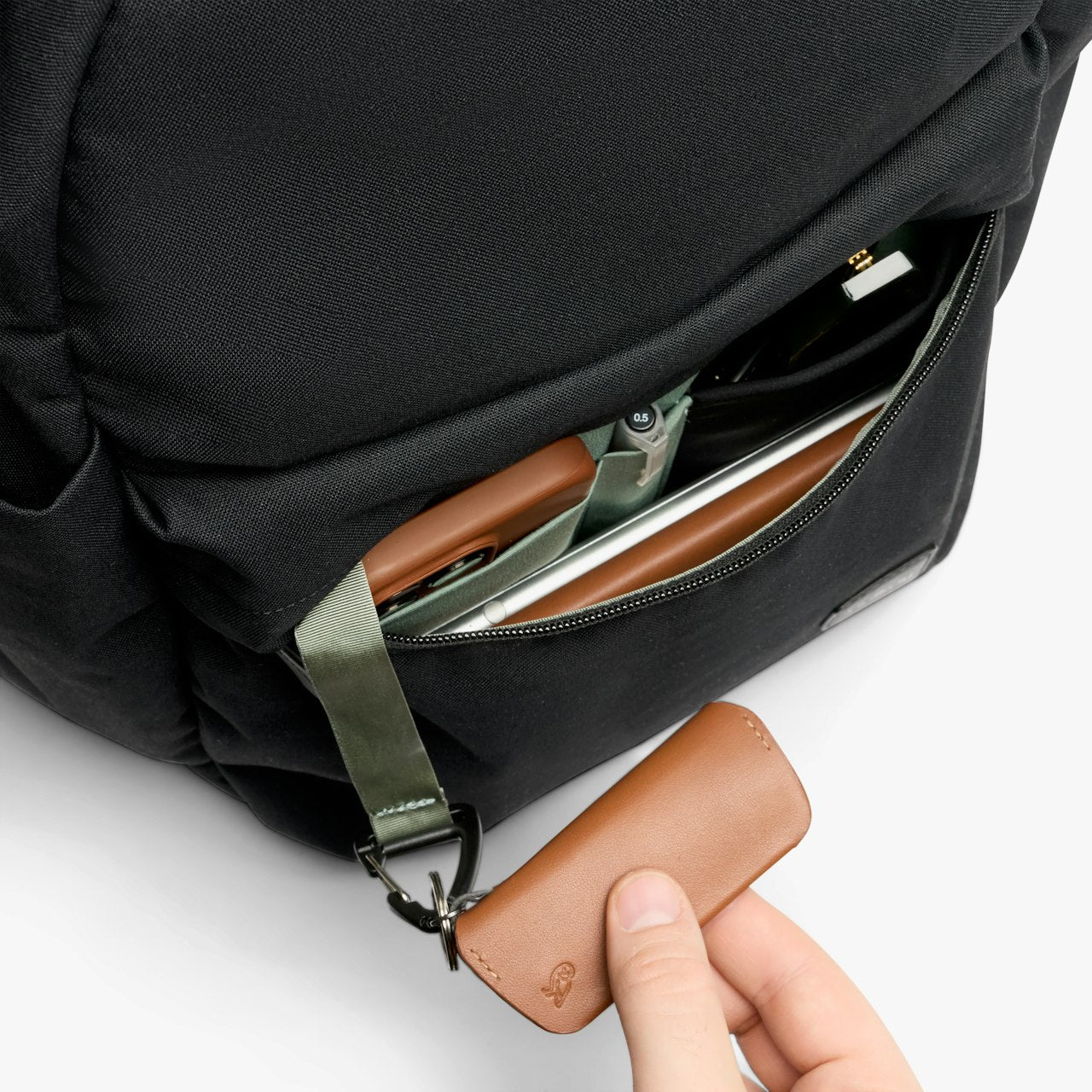 Black daypack side zipper detail with leather pull tab and small interior card slots