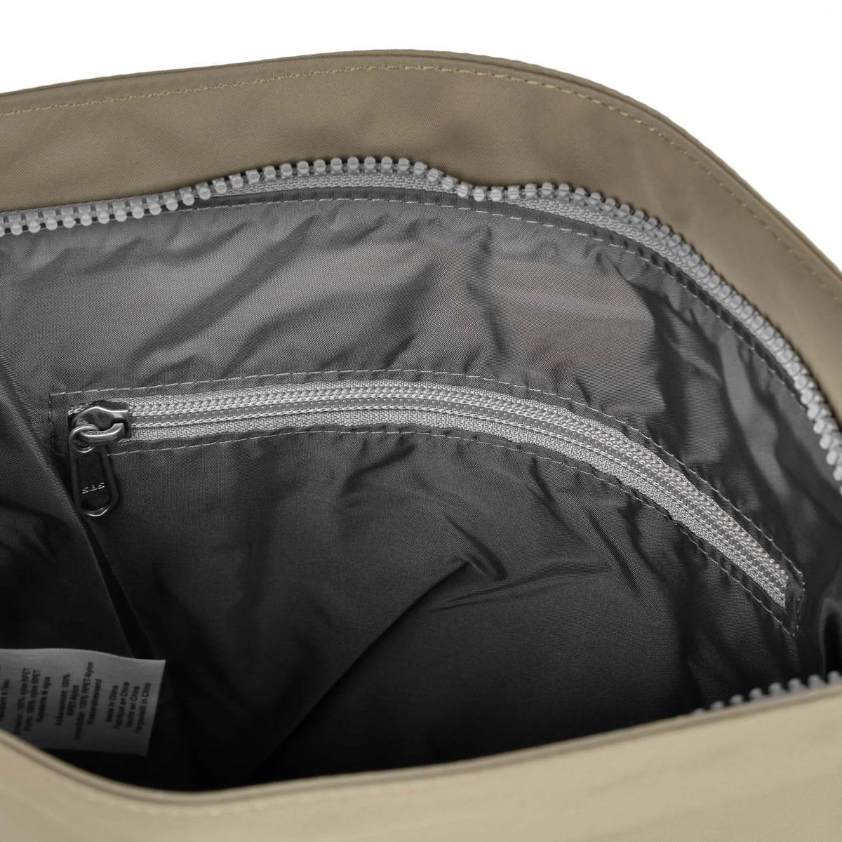 Beige crossbody bag interior with zippered compartments and gray zipper pulls